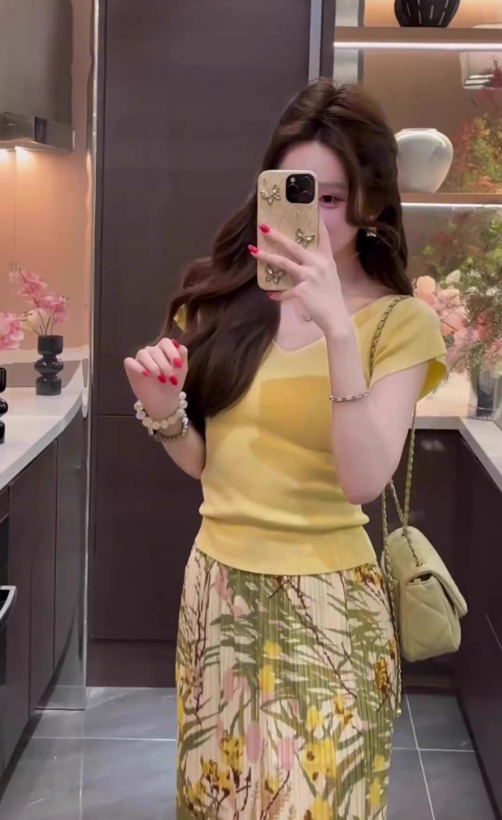 The queen is wearing a beautiful yellow short-sleeved T-shirt and floral skirt on vacation R0900