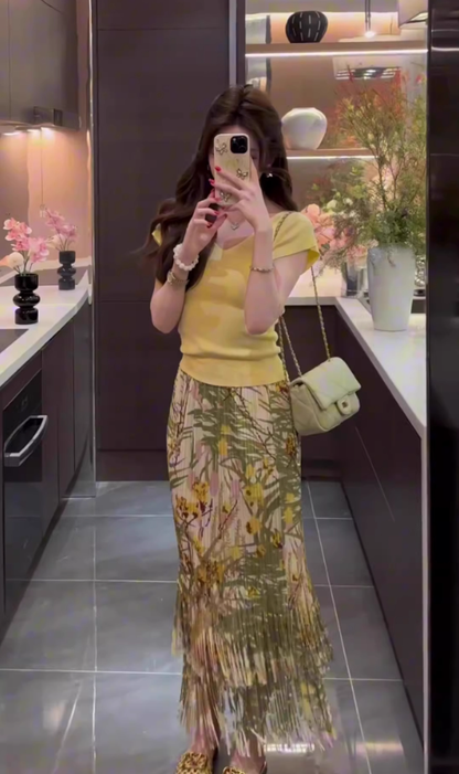 The queen is wearing a beautiful yellow short-sleeved T-shirt and floral skirt on vacation R0900