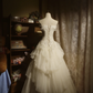 White strapless ball gown with a cinched waist and a voluminous tiered cake skirt; bridal gown R7289