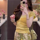 The queen is wearing a beautiful yellow short-sleeved T-shirt and floral skirt on vacation R0900